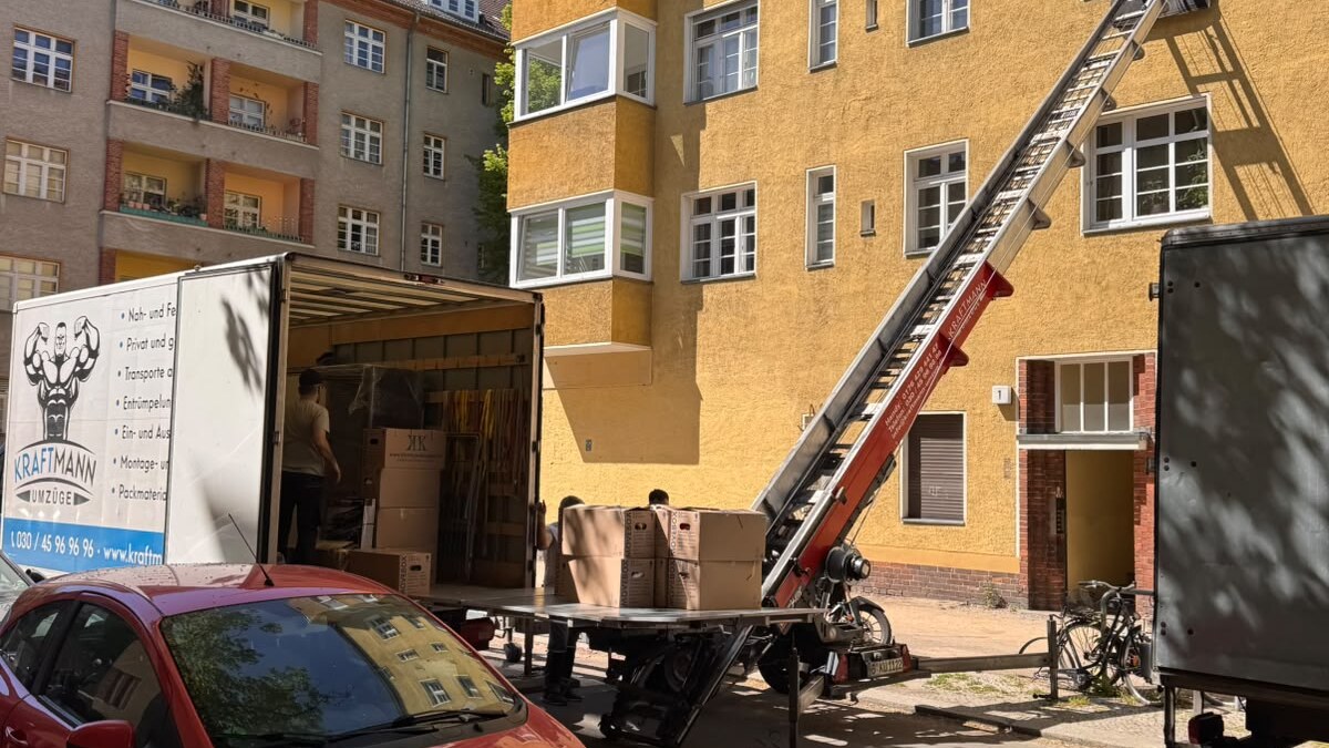 Erste eigene Wohnung – Umzugswagen und Möbellift vor einem gelben Altbau